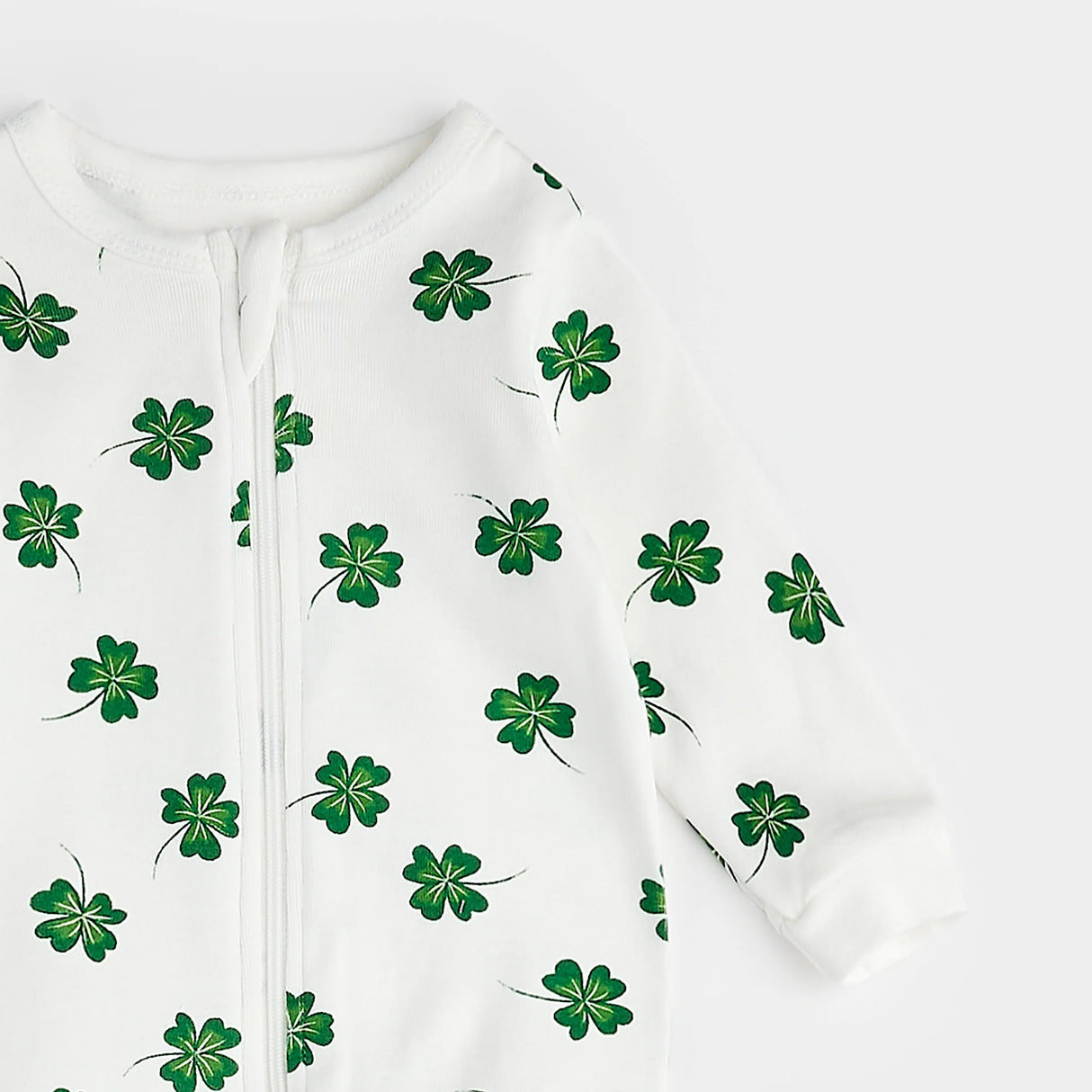 Close-up of green clover print on organic cotton baby footed sleeper