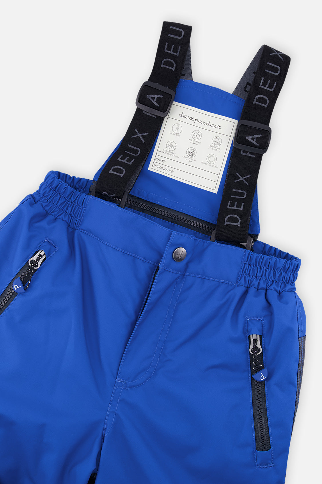 Close-up of the blue PLAY snow pants waist, zip pockets and logo suspenders