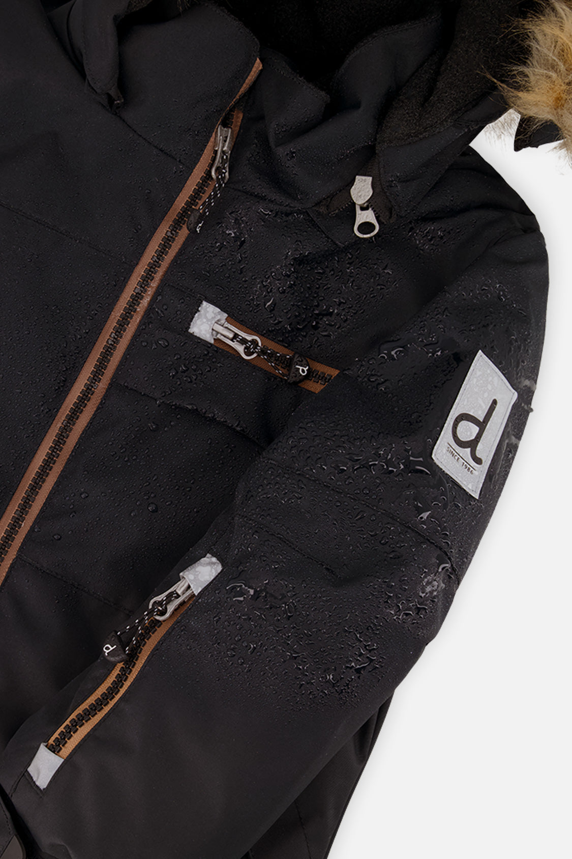 Close-up of the black PLAY jacket front zipper, chest pocket and sleeve logo patch
