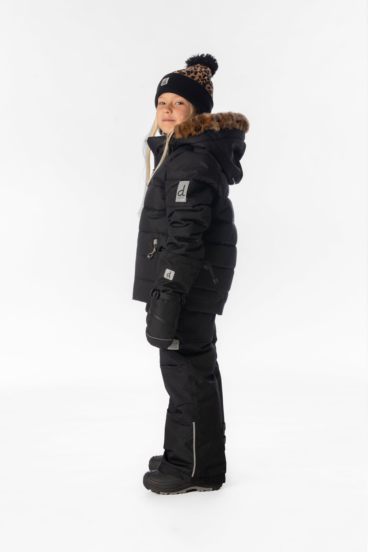 Girl in the black Deux par Deux PLAY snowsuit with leopard faux-fur trim, side view