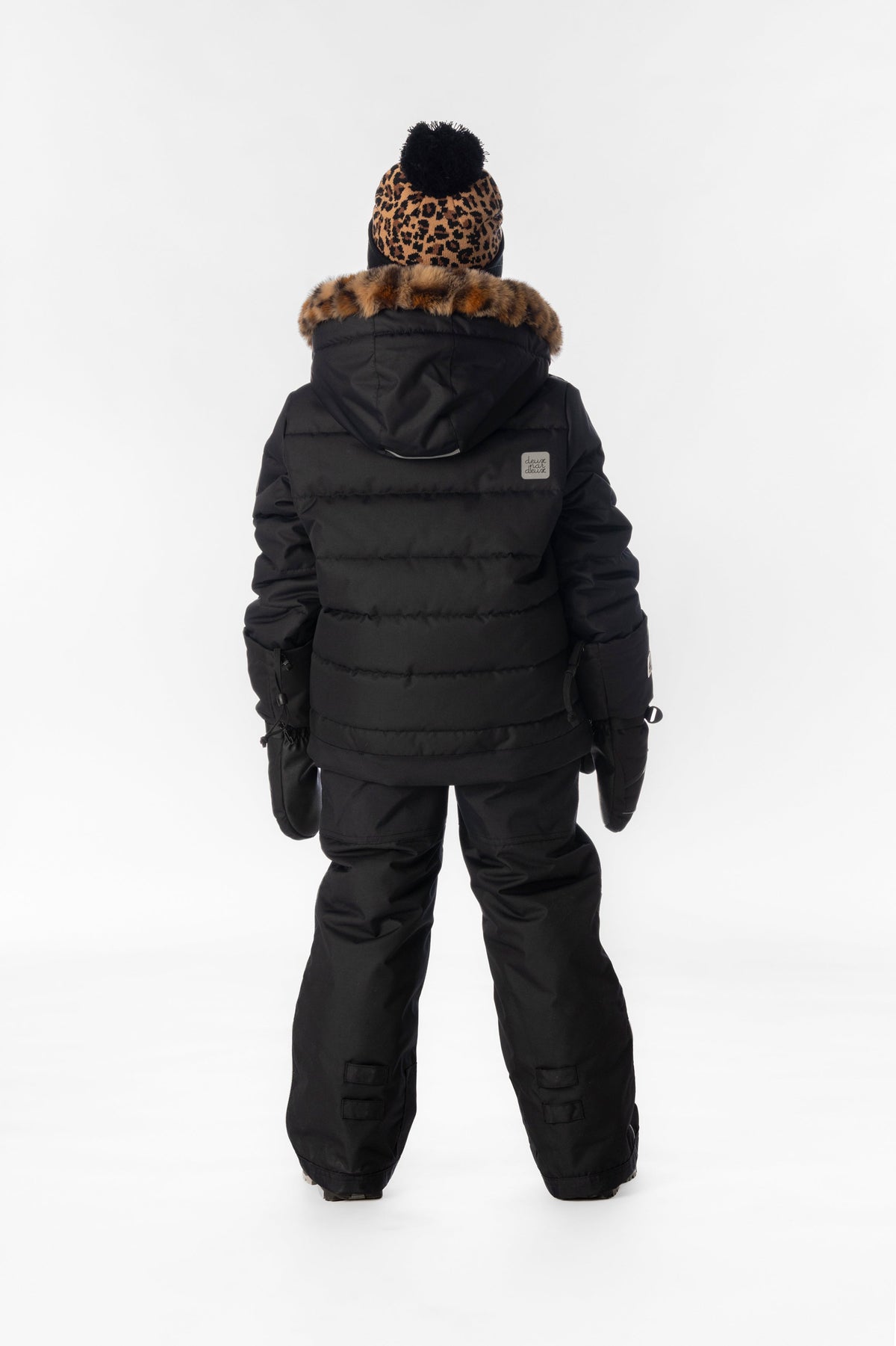 Girl in the black Deux par Deux PLAY snowsuit with leopard faux-fur trim, back view