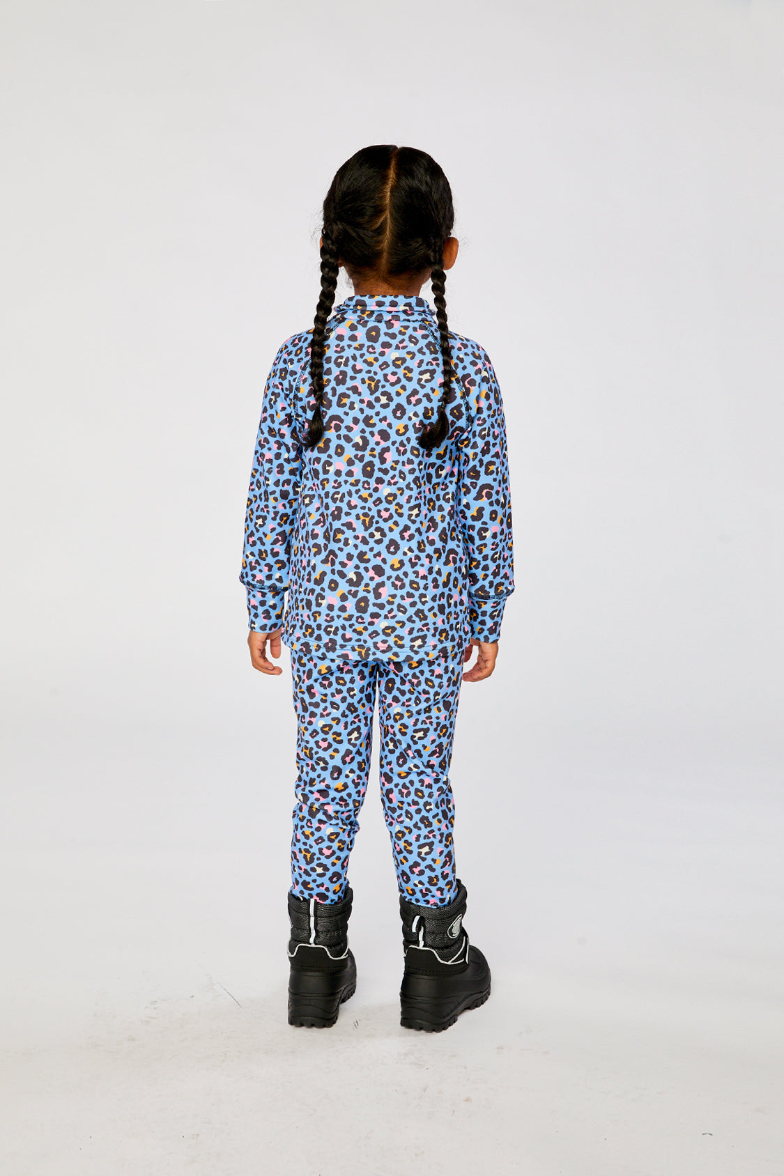 Child wearing the blue leopard print Deux par Deux thermal underwear set with black boots, back view
