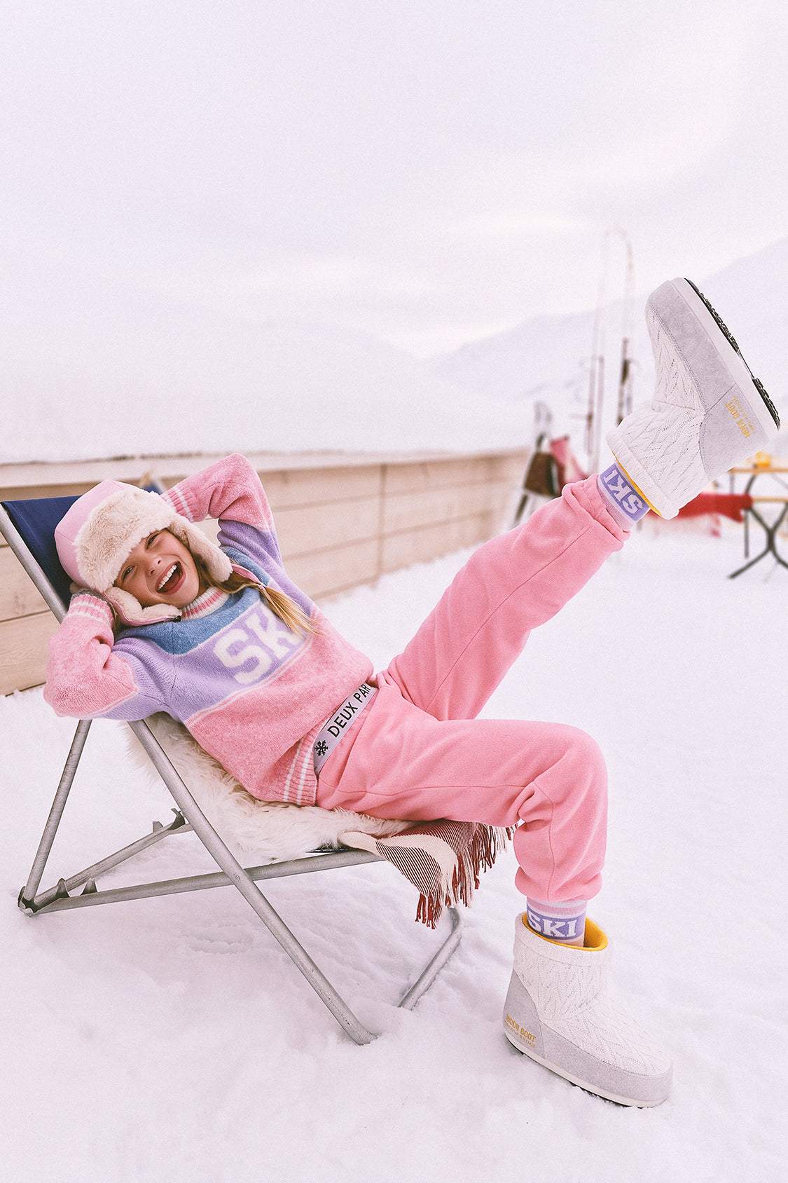 Girl relaxing in a deck chair in the snow wearing Deux par Deux thermal leggings in light pink