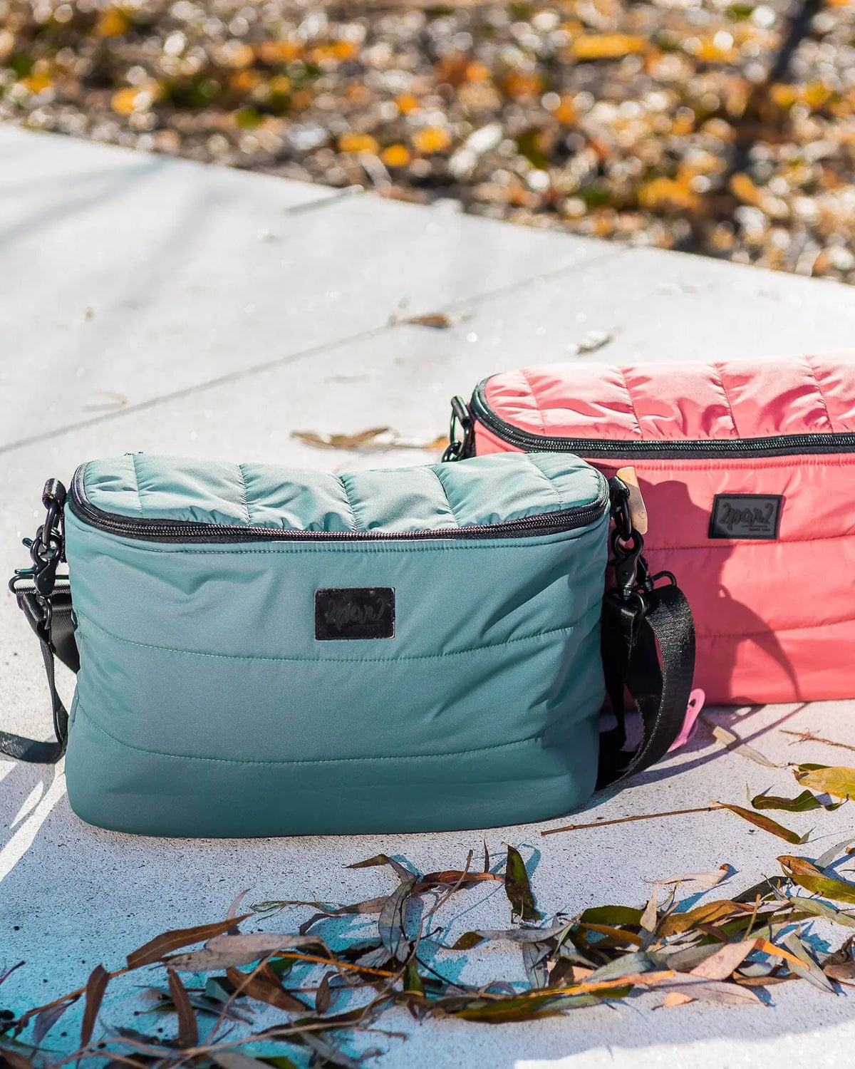 Sage green and coral quilted mini bags side by side on a sunny stone step