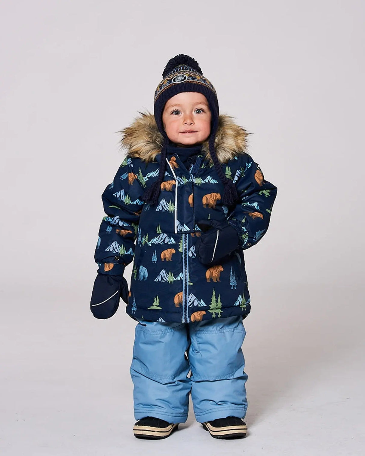Toddler boy wearing blue/gray jacket and snow pants set with fleece-lined bib.