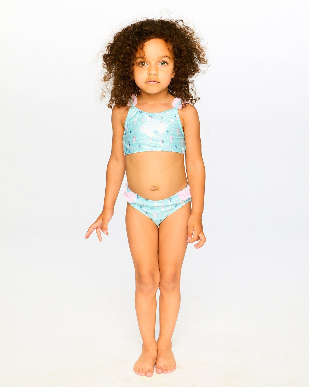 Girl wearing Deux par Deux blue seahorse two-piece swimsuit for a sunny pool or beach day.
