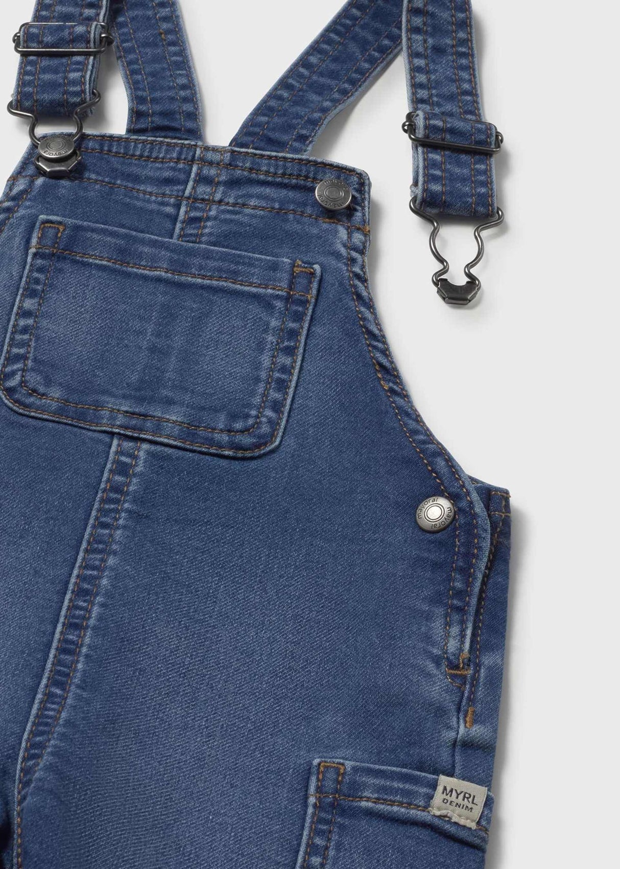Closeup of Mayoral baby denim dungaree showing pocket detail, strap hardware, and cotton-blend fabric.