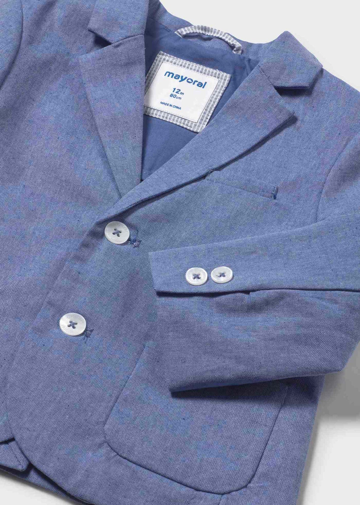 Closeup of Mayoral baby blazer showing collar, button closure, and cotton-linen texture.
