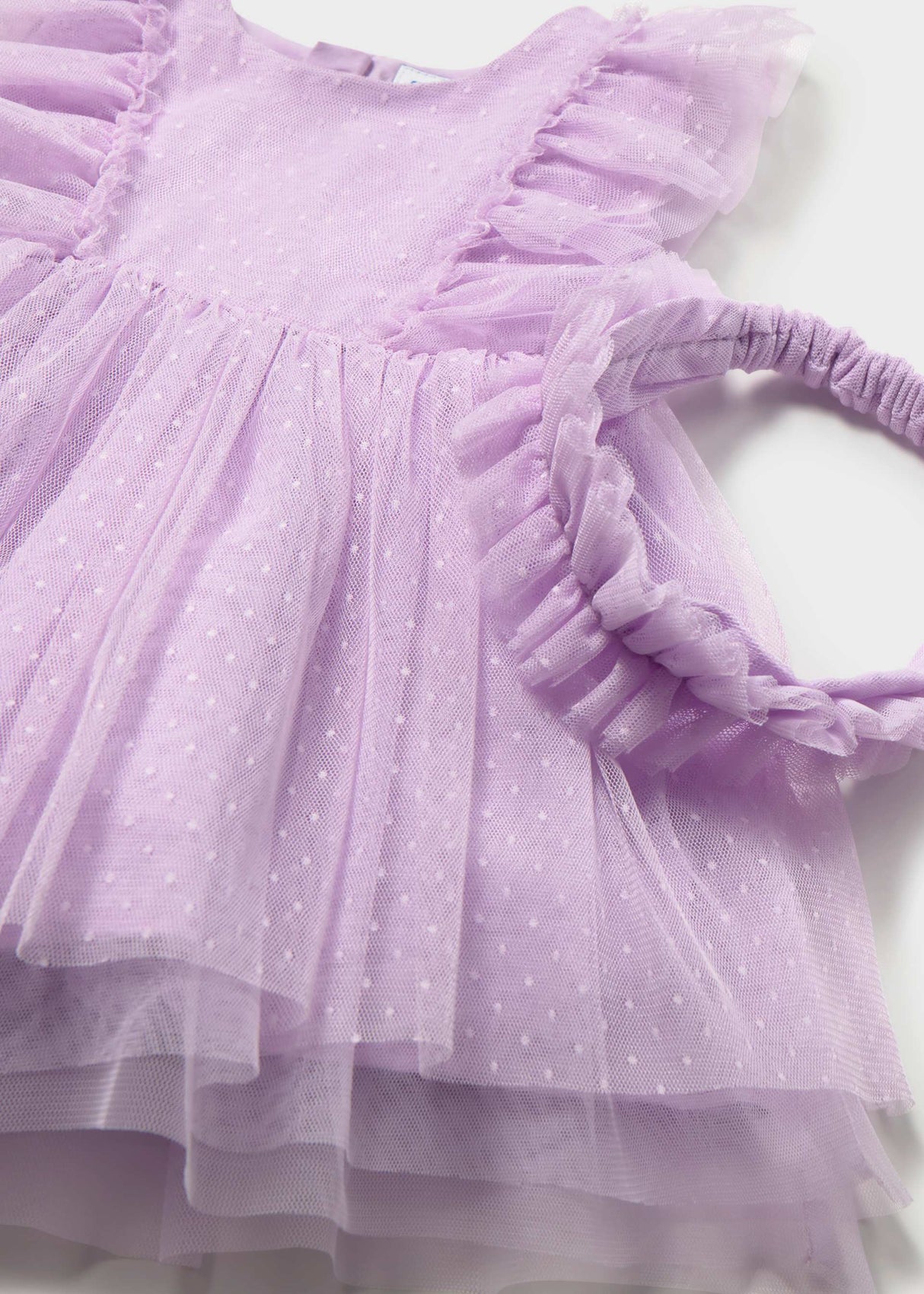 Closeup of Mayoral baby tulle dress showing Swiss dot texture, ruffle detail, and matching headband.