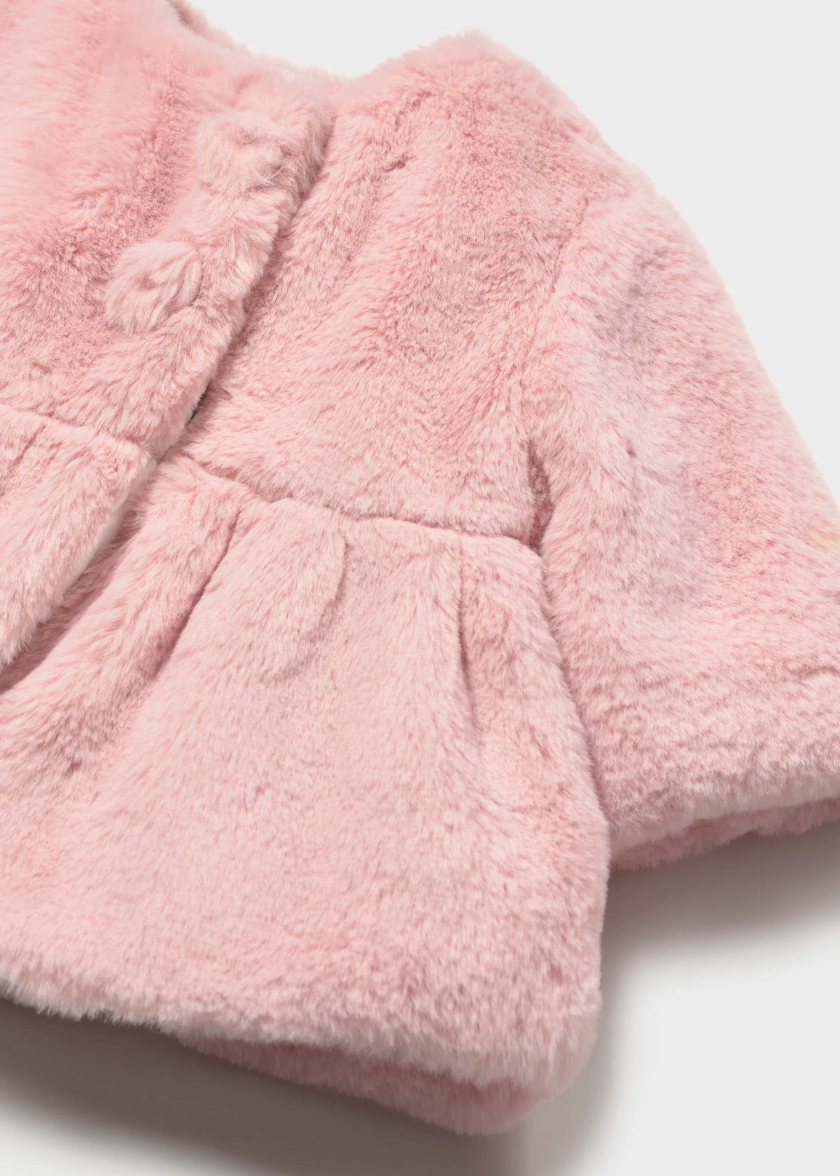 Close-up of pink faux fur fabric and a pom-pom button