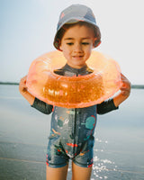 Baby boy playing at the beach wearing blue marine animals rashguard one-piece and sun hat