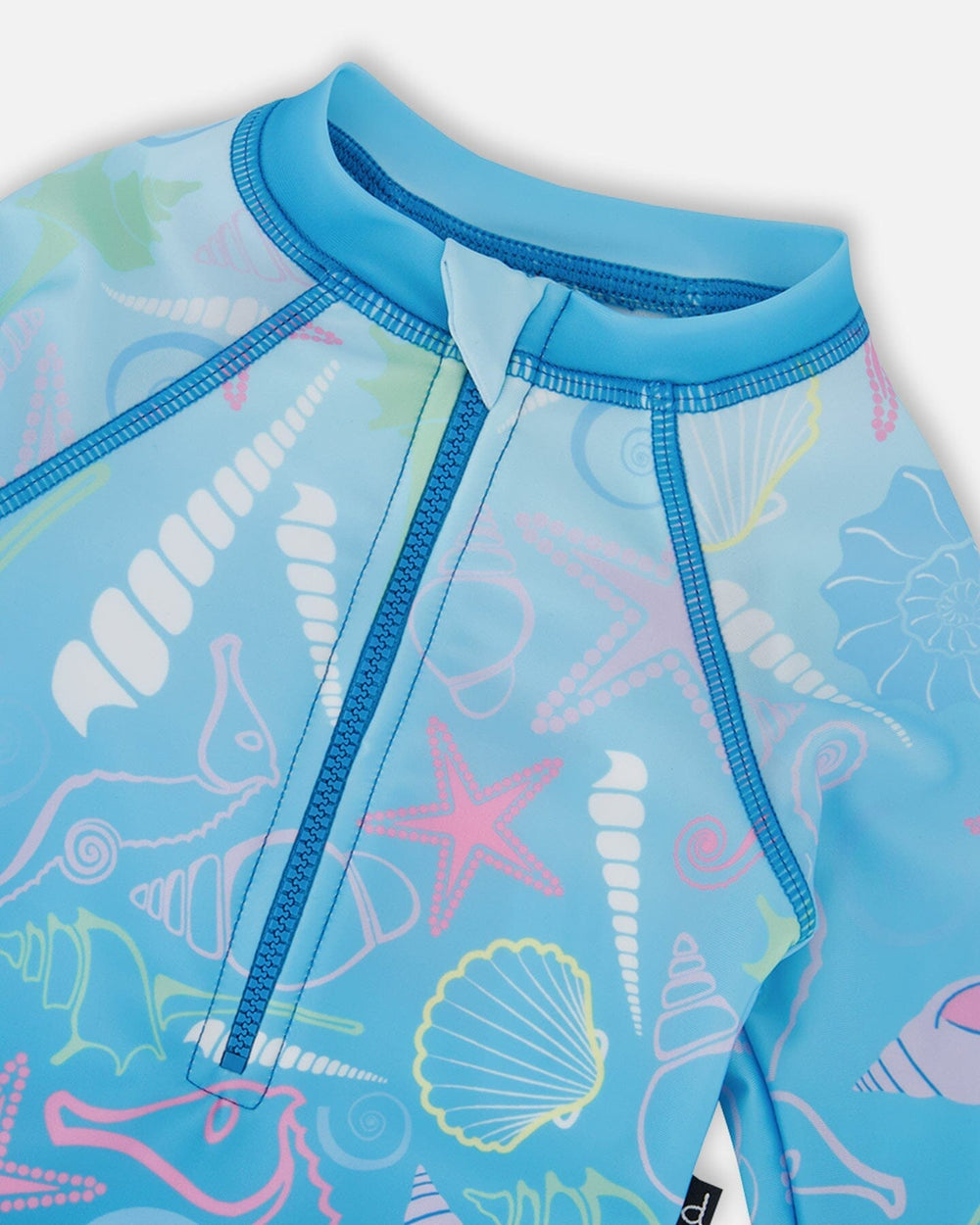 Close-up of neckline, zipper, and pastel shell print on blue girl rashguard swimsuit