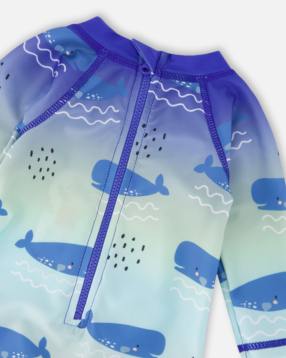 Detail shot of zipper, neckline, and whale pattern on blue rashguard swimsuit