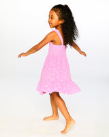 Girl twirling in pink flower cover-up dress showing movement of tiered skirt