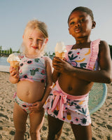 Two girls at the beach wearing fruity pink cover-up skirt layered over swimsuits