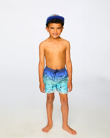 Boy in studio wearing blue beach print swim shorts front view