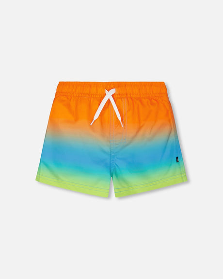 Front flat lay of Deux par Deux baby and boy boardshorts in orange blue green gradient