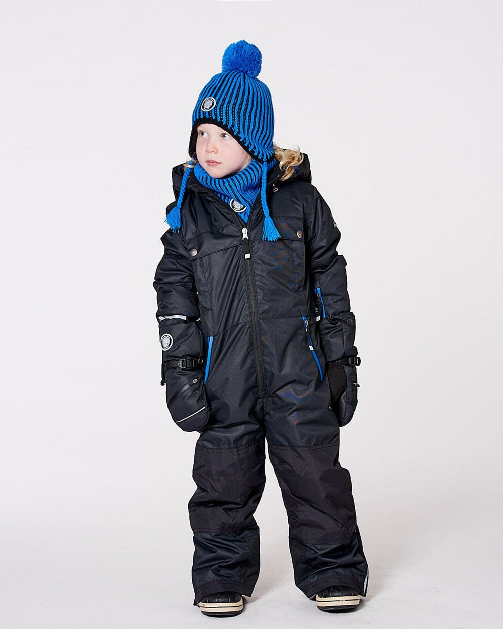 Child wearing black one-piece Teknik snowsuit – front on snow