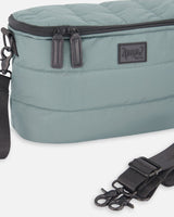 Close-up of the faux leather zipper pulls, logo patch and black stroller clip on the quilted bag
