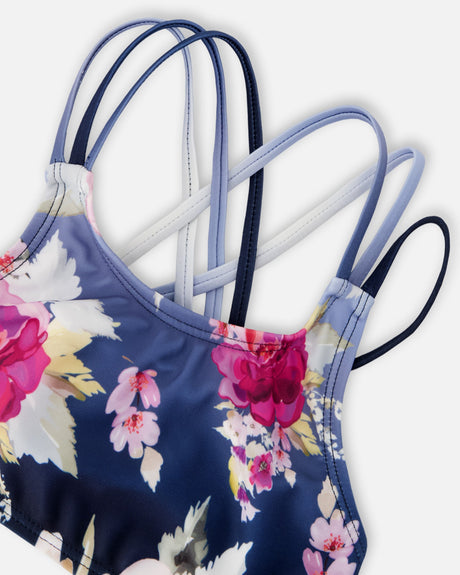 Detail of the pink rose print below the crossed straps of the blue rose swim top
