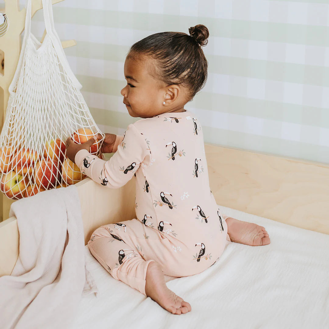 Infant wearing toucan print convertible sleeper with two-way zipper