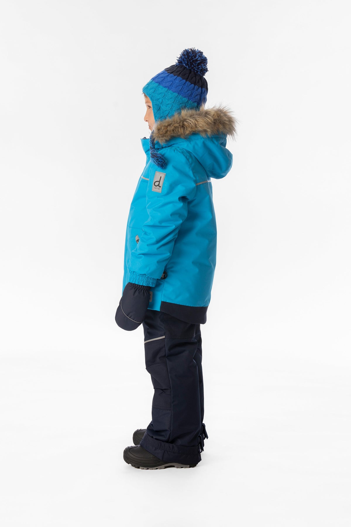 Boy in the bright blue and navy Deux par Deux DISCOVER snowsuit, side view