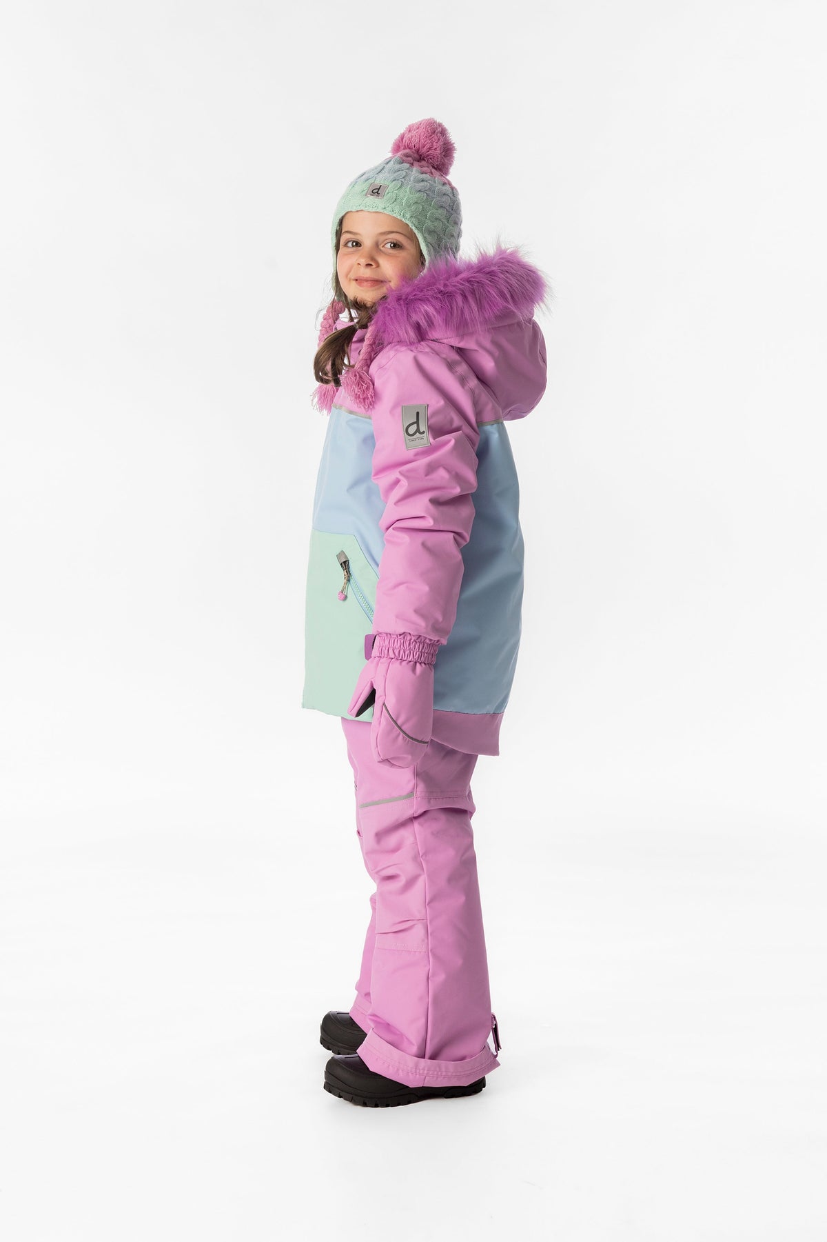 Girl in the pinkish violet colour-block Deux par Deux DISCOVER snowsuit, side view