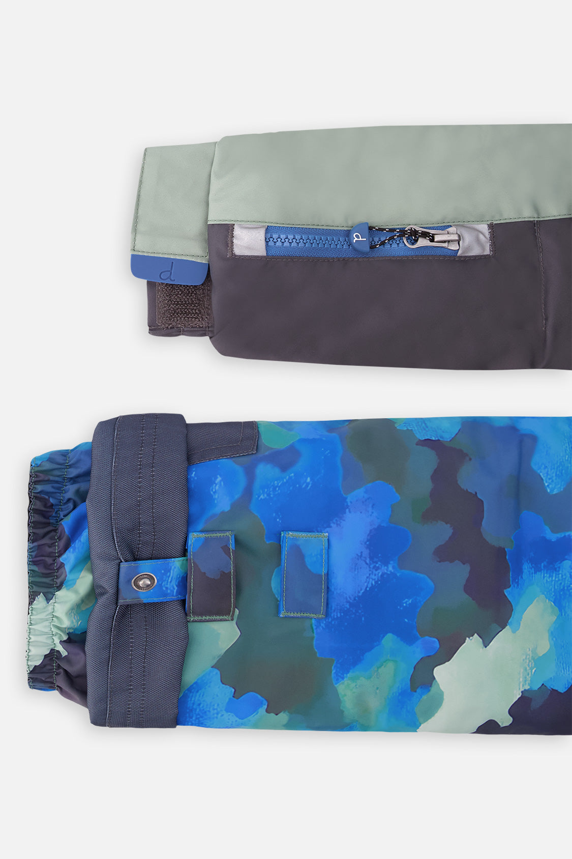 Close-up of the PLAY jacket sleeve ski-pass pocket and the adjustable camouflage pant hem