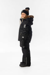 Girl in the black Deux par Deux PLAY snowsuit with leopard faux-fur trim, side view