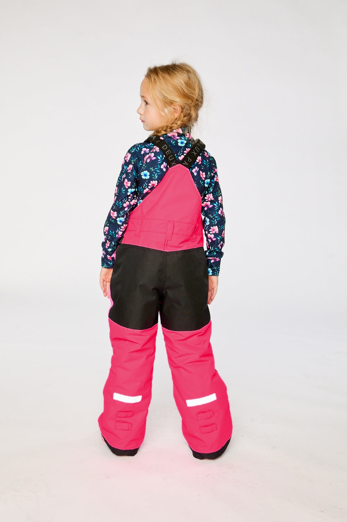 Back view of a girl in the bright pink snow bib with reflective hem trims