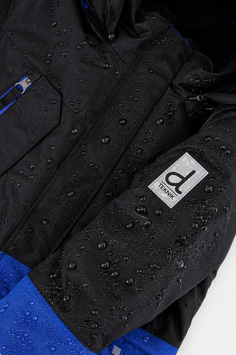 Deux par Deux boys' Teknik two-piece snowsuit in black and royal blue – logo badge close-up