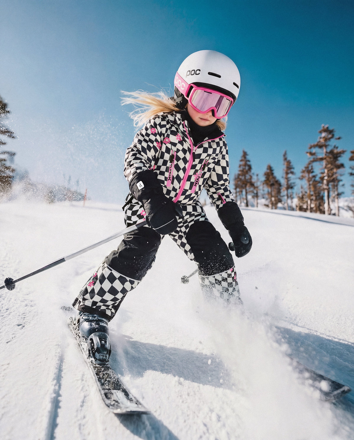 Child wearing the Deux par Deux white and bright pink checkered TEKNIK snowsuit, lifestyle view