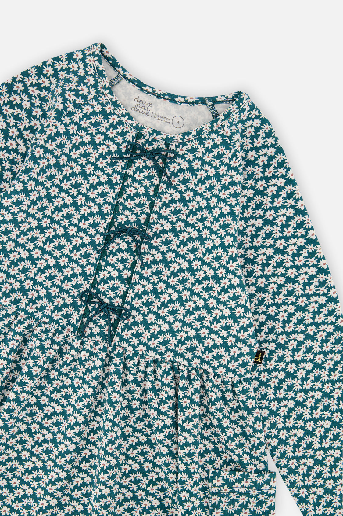 Close-up of the small bows and ditsy floral print on the green organic cotton dress