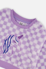 Close-up of the embroidered unicorn and the shoulder buttons and ribbed neckline on the lilac faux fur top