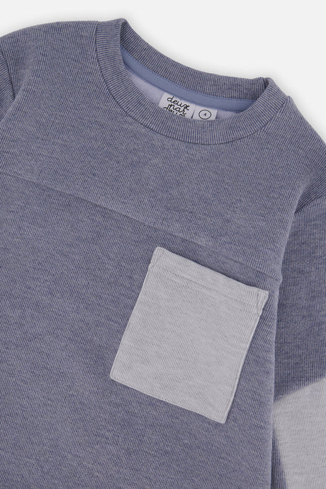 Close-up of the ribbed crew neck and light gray chest pocket on the blue top