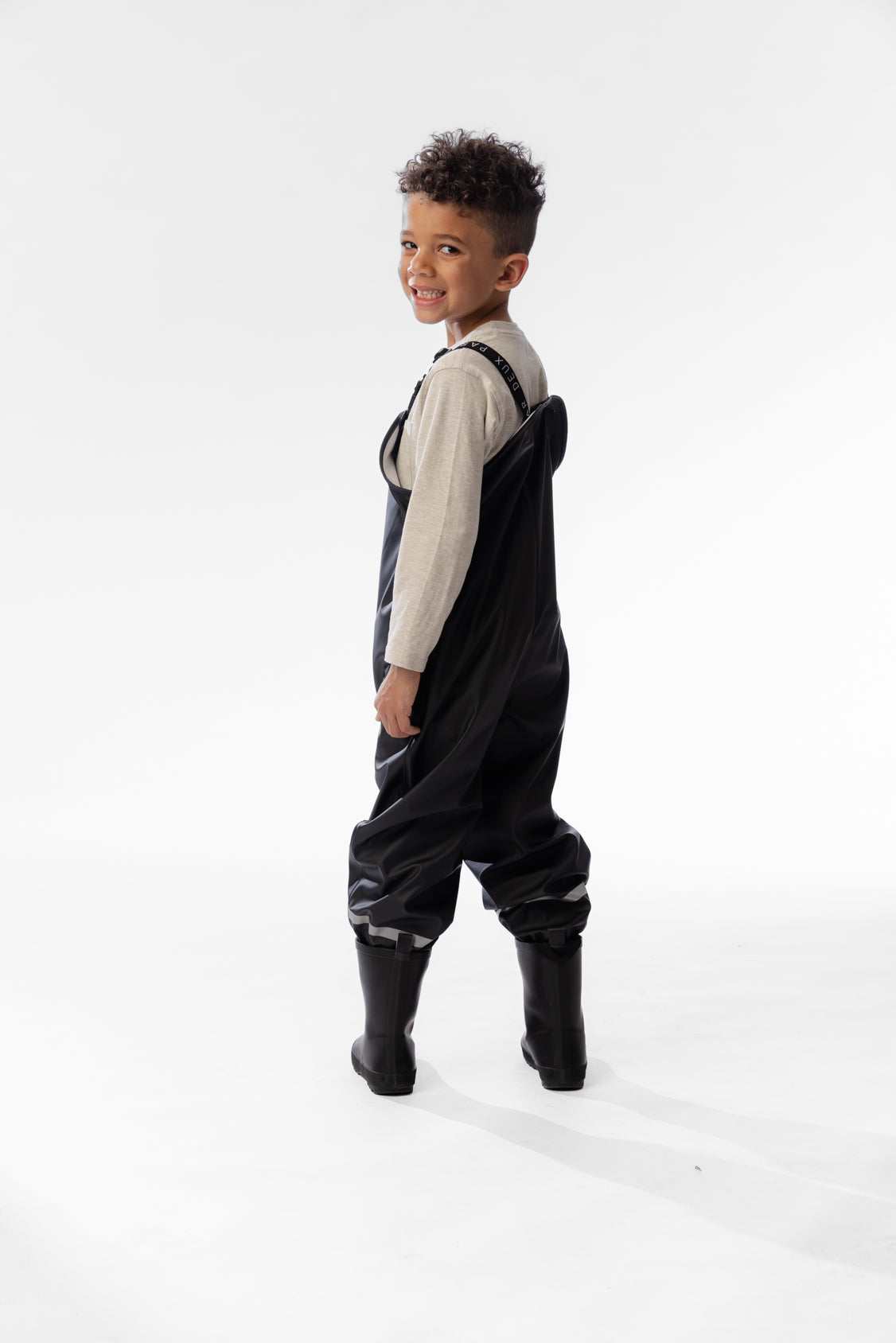 Child in the Deux par Deux black waterproof rain overalls, lifestyle photo