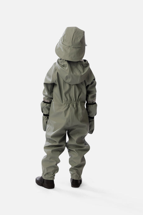 Lifestyle photo of a child wearing the Deux par Deux sage green colorblock rain one-piece
