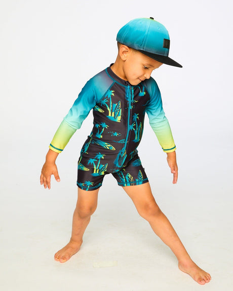 Boy posing in studio in black surf long sleeve rashguard romper front view