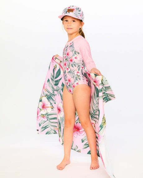 Girl walking on the beach in pink hibiscus rashguard swimsuit with matching cover-up