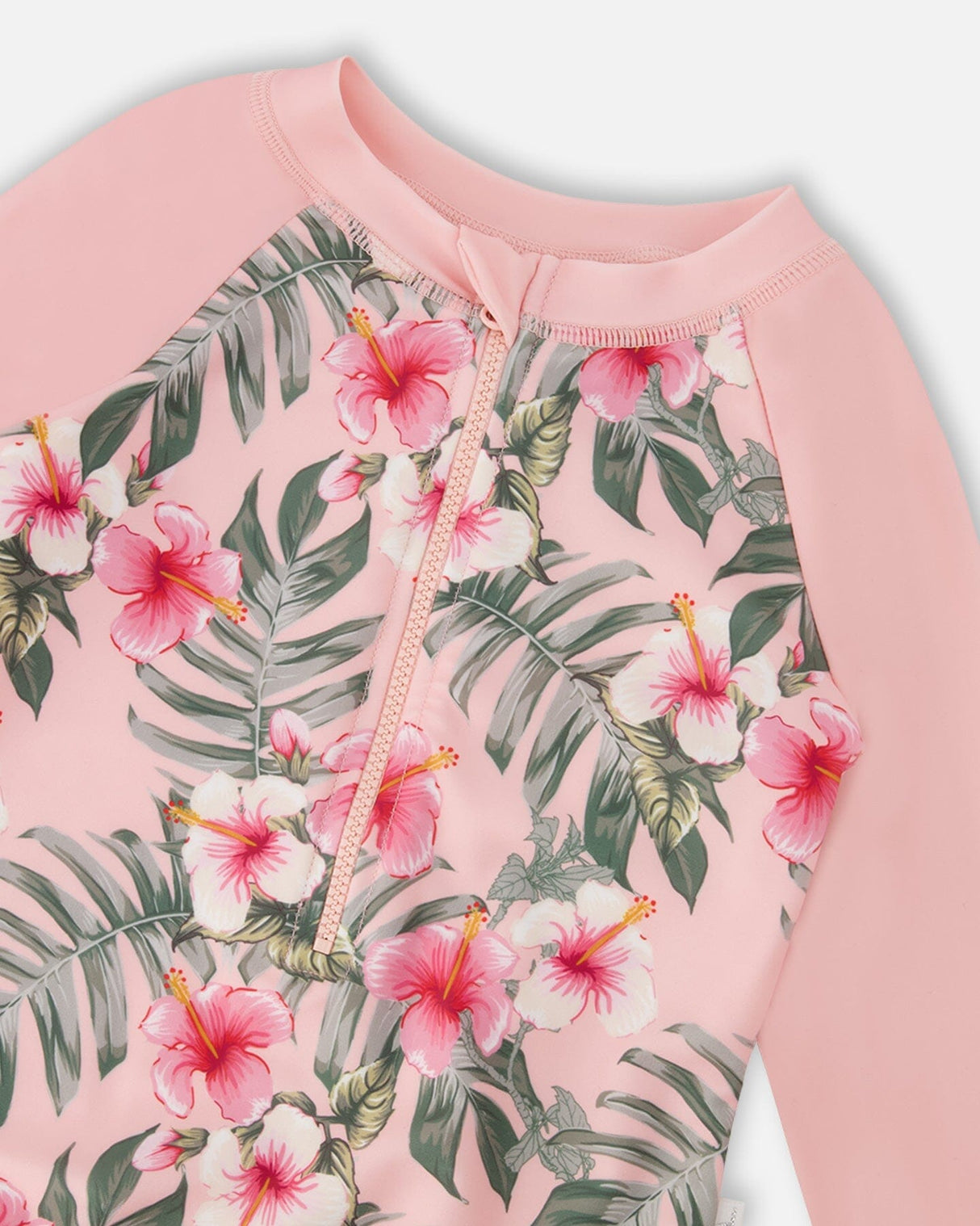 Close-up of hibiscus floral print and solid pink sleeves on girl rashguard swimsuit