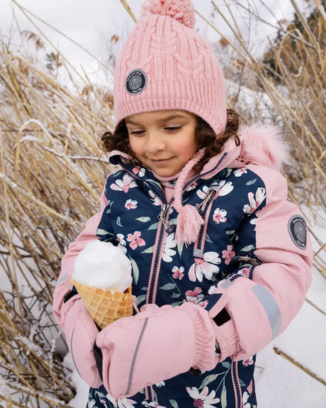 Girl wearing navy flower kids snowsuit with pink faux fur hood outside
