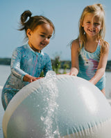 Two girls playing with beach ball, one in aqua seahorse kids swimsuit
