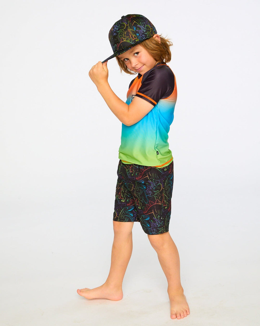 Side view of boy in orange blue green rashguard swim shirt and shorts