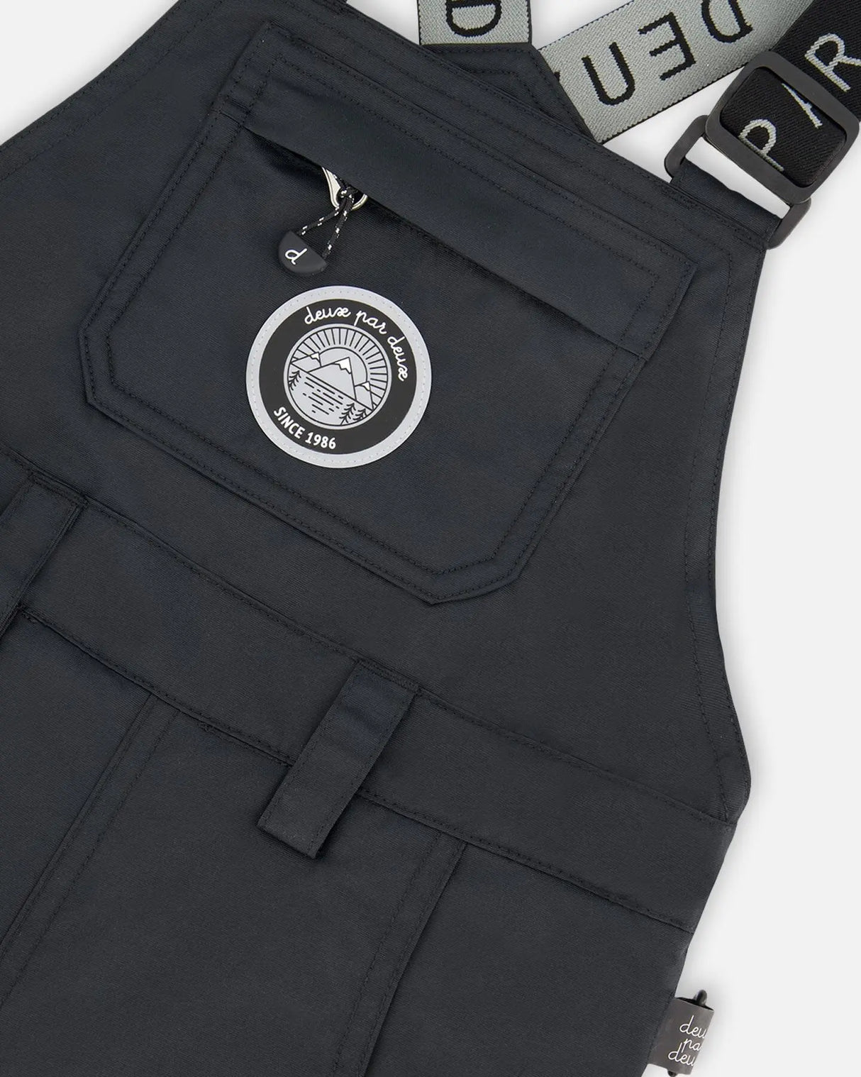 Closeup of Cordura® reinforced black bib overall with logo patch.