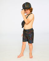Boy in studio wearing black neon dinosaur swim shorts side view