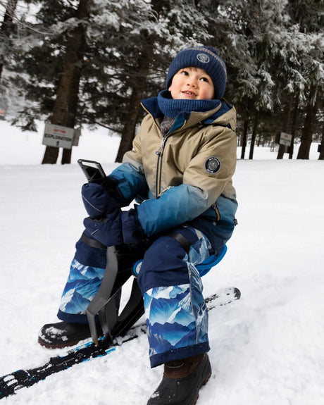 Action shot in blue jacket and snow pants, detachable hood and snow skirt.