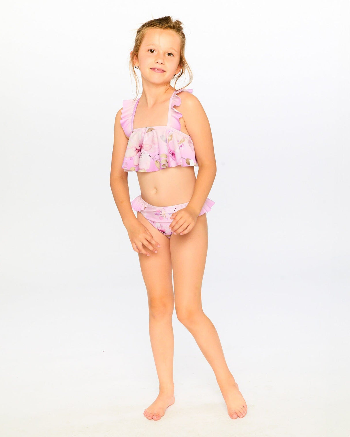 Studio front view of girl wearing purple floral two-piece swimsuit showing flared top