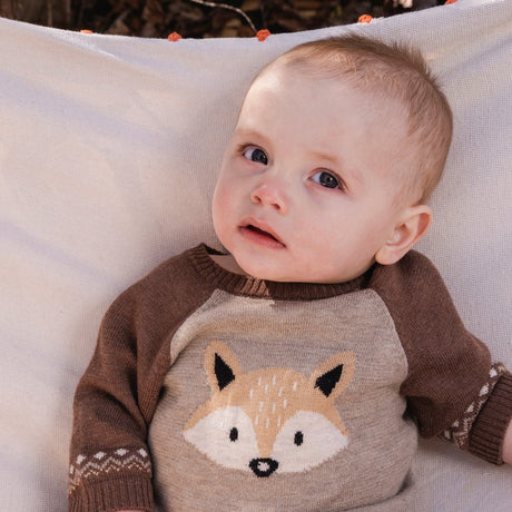 Baby boy in a Deux par Deux brown knitted romper with a fox design