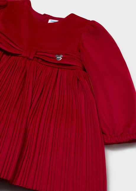 Close-up of the bow and small heart charm on the red pleated dress