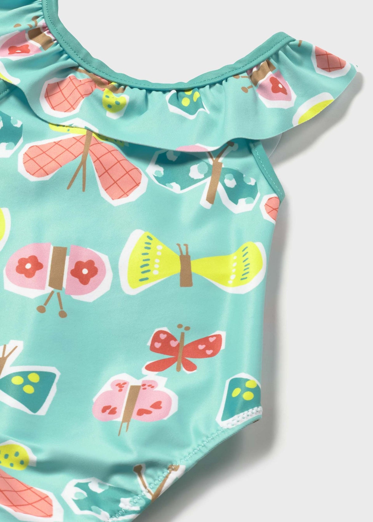 Closeup of Mayoral baby girl UPF swimsuit showing fish print, ruffle trim, and Aqua swim fabric.